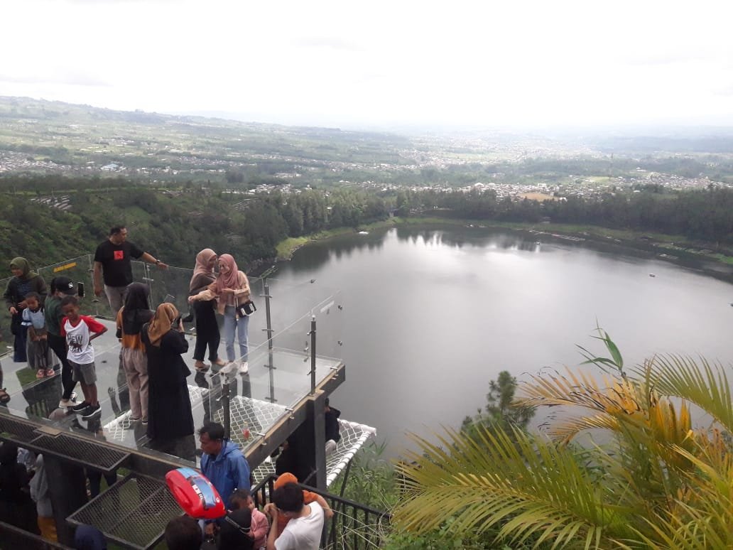 PENGUNJUNG. Sejumlah pengujung menikmati liburan tahun baru dari jembatan Kaca Sky Line Bukit Seroja kawasan Telaga Menjer Kecamatan Garung.