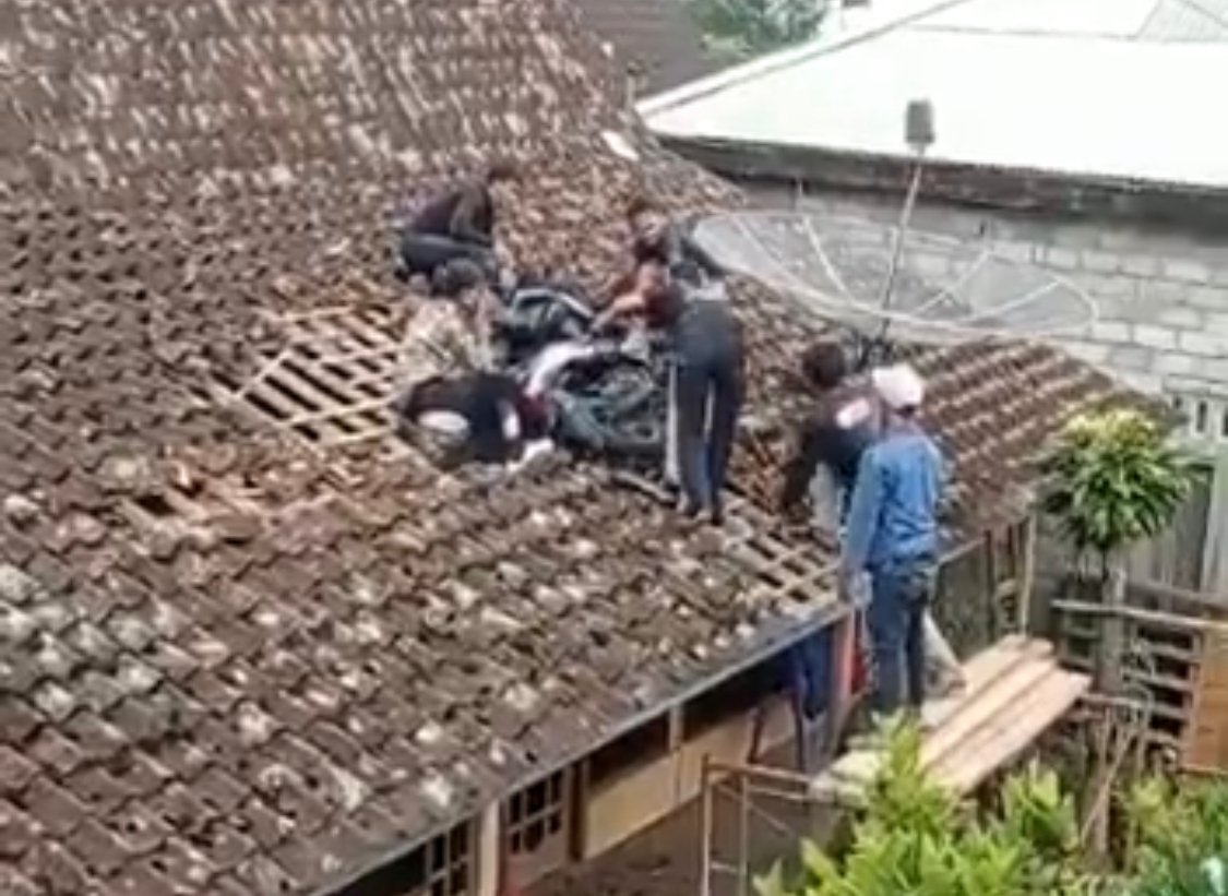 KECELAKAAN. Seorang perempuan pengendara sepeda motor yang terjatuh di atap rumah warga di Ngablak, Kabupaten Magelang, hendak ditolong warga, Senin, 16 Januari 2023.